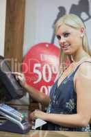 Woman is typing at the till while smiling