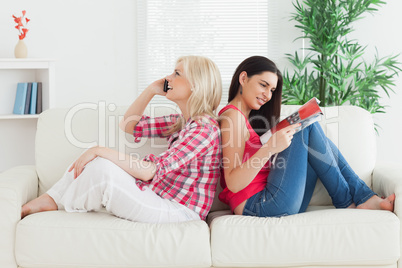 Women sitting back to back on couch