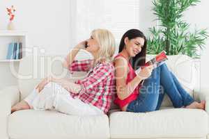 Women sitting back to back on couch