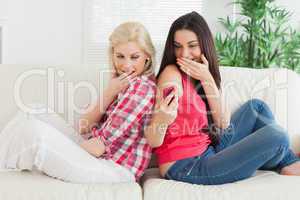 Woman  showing text message to friend and laughing