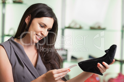 Woman looking at price tag of shoe and smiling