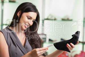 Woman looking at price tag of shoe and smiling