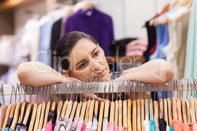 Woman leaning on a clothes rack looking thoughtful
