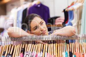 Woman leaning on a clothes rack looking thoughtful