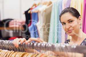 Woman standing by clothes rack