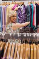 Woman standing by the clothes rack smiling