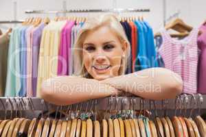 Woman leaning on clothes rack smiling