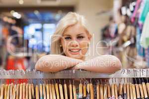 Woman leaning at a clothes rack smiling