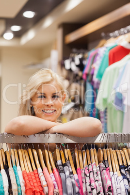 Woman leaning at a clothes rack while smiling