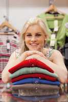 Woman is leaning on clothes and smiling