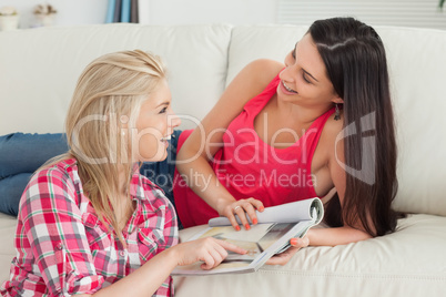 Women lying on the couch looking at a catalog