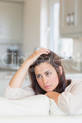 Woman thinking and sitting on couch