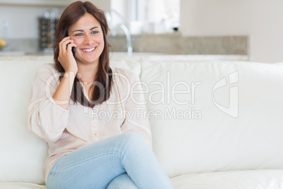 Woman phoning while sitting on the couch