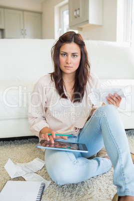 Brunette calculating bills on tablet pc