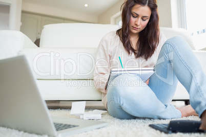 Woman sitting on the carpet and calculating bills