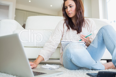 Woman typing on the laptop and comparing bills