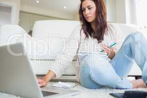 Woman typing on the laptop and comparing bills
