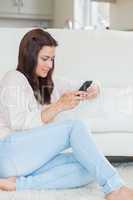 Woman sitting on the carpet and texting