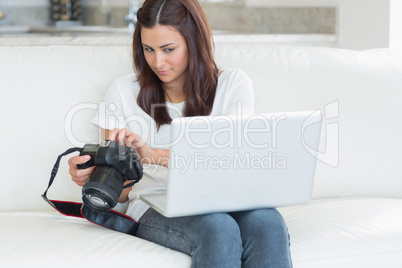 Woman looking at laptop while holding a camera