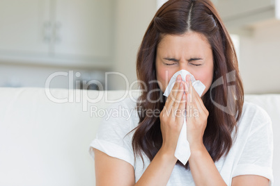 Brunette sneezing in a tissue