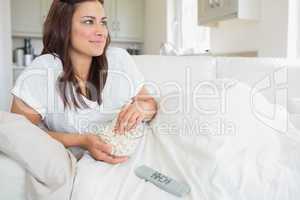 Woman watching television and eating popcorn