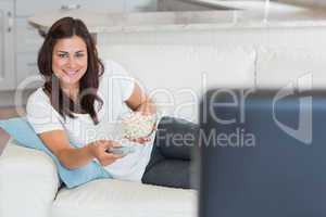 Brunette smiling while watching television