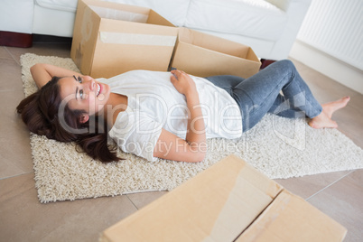 Woman lying on the carpet surrounded by moving boxes