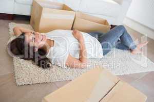 Woman lying on the carpet surrounded by moving boxes