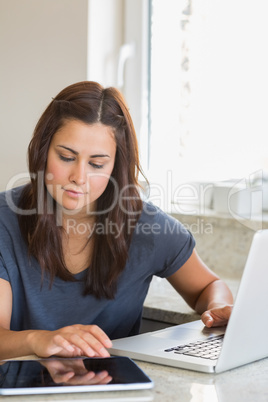 Brunette typing on the tablet pc and laptop