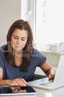 Brunette typing on the tablet pc and laptop