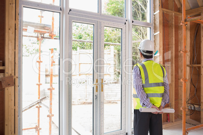 Architect holding a plan while looking outside