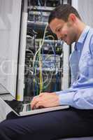 Man using laptop in front of servers