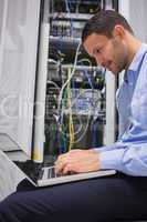 Man using laptop beside servers