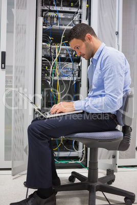 Man on his laptop beside servers