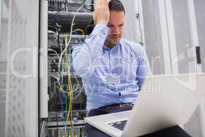 Man getting stressed with laptop over servers