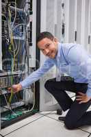 Smiling man adjusting cable in the server