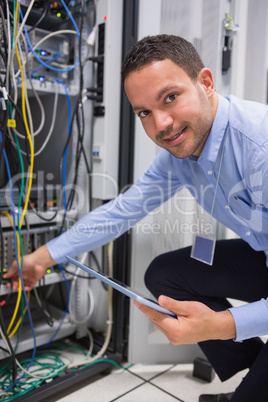 Technician plugging in cables and using tablet pc