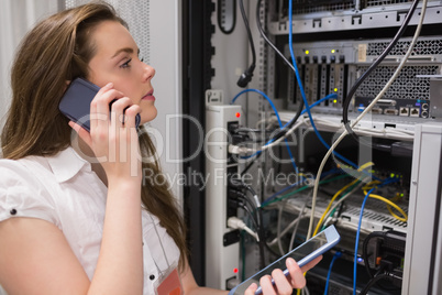 Woman working on servers with tablet pc on the phone