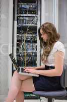 Woman using laptop in front of servers