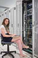 Happy woman with laptop working with servers