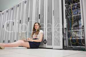 Happy woman sitting on floor working on laptop