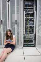 Woman working on servers with tablet pc sitting on floor