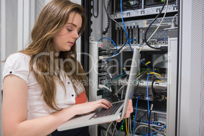 Woman using laptop to work on servers