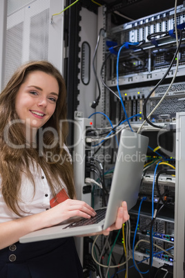 Woman happily using laptop to work on servers