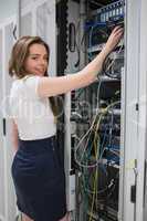 Smiling brunette fixing wires of server