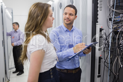 Two people checking servers with one holding clipboard