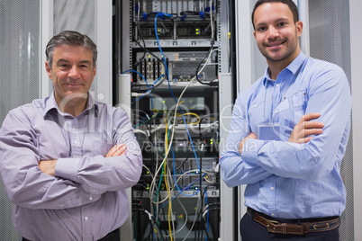 Technicians smiling while standing in front of servers