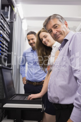 Three happy technicians checking servers with laptop