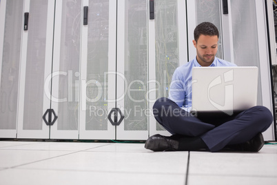 Technician sitting on floor working on laptop