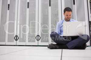 Technician sitting on floor working on laptop